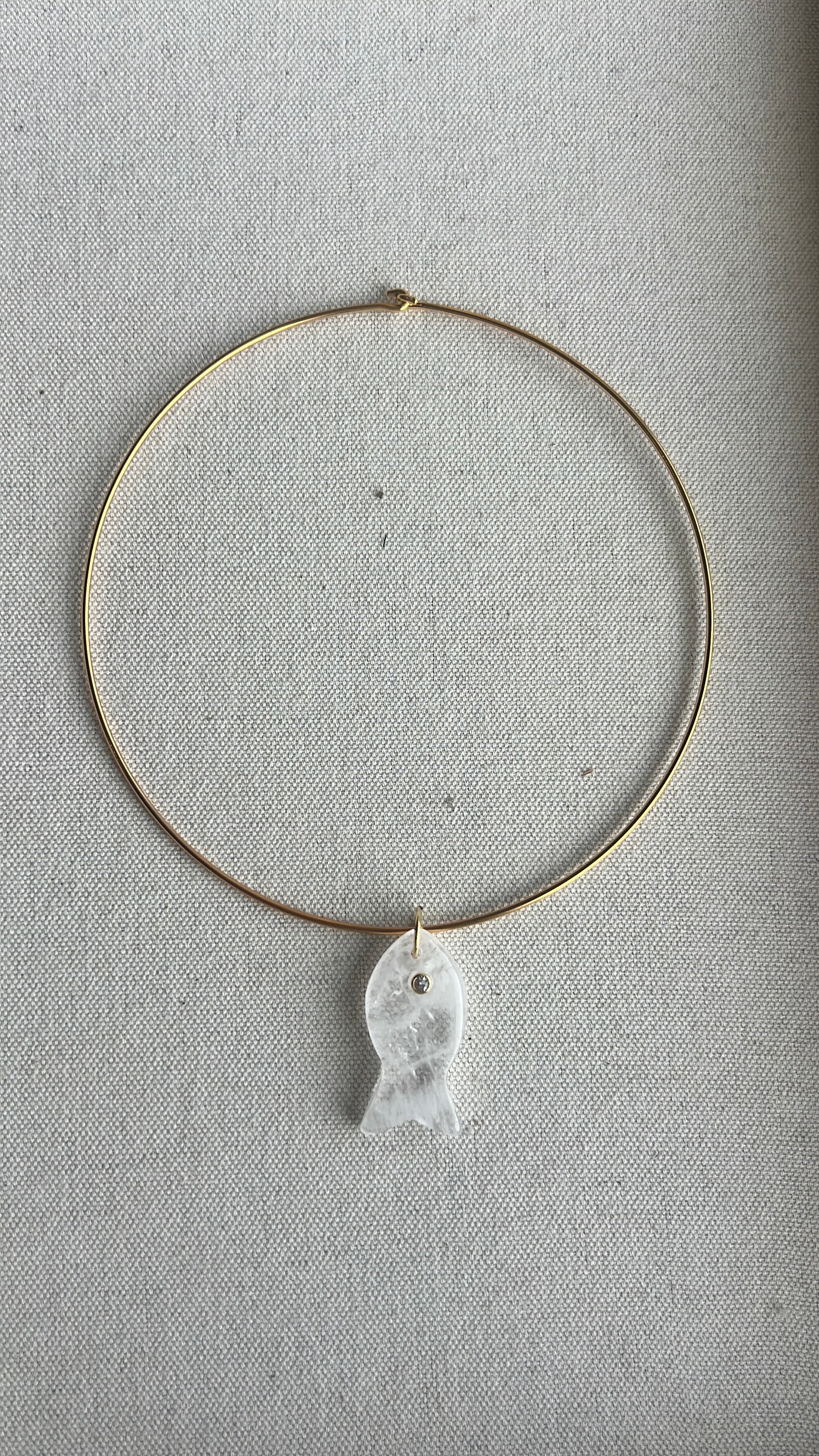 Necklace with a white fish pendant on a gray background